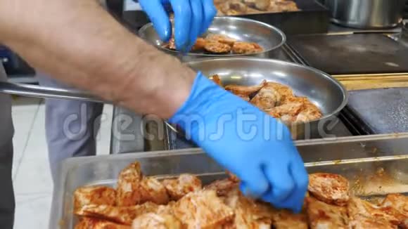 很多卡住的肉是在一家餐馆的两个煎锅里炸的厨师的手变成了蓝色的手套一个厨房视频的预览图