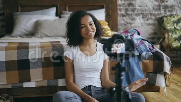 快乐的混血女人用dslr相机在家中记录她的衣柜视频的预览图