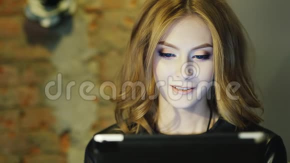 一位年轻的女士微笑着在咖啡馆里享受着平板电脑视频的预览图