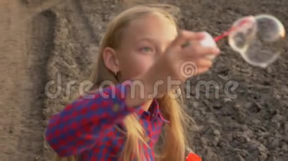 年轻女孩在户外吹肥皂泡少女乡村之路关闭未聚焦慢动作视频的预览图