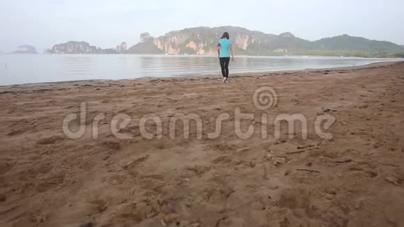 女孩走路开始沿着海滩跑步视频的预览图