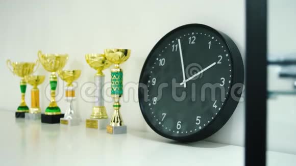 奖杯奖为获奖者在货架上展示库存架子上的时钟和奖杯时间和运动的概念视频的预览图