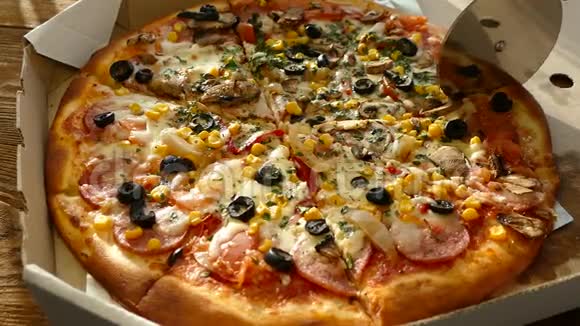 在盒子里送披萨一个美味多汁和美丽的披萨是用圆刀切割的一家人吃披萨视频的预览图