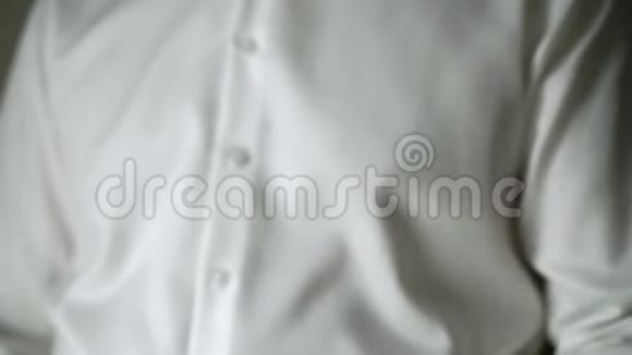 穿白色衬衫的年轻人戴上袖扣视频的预览图