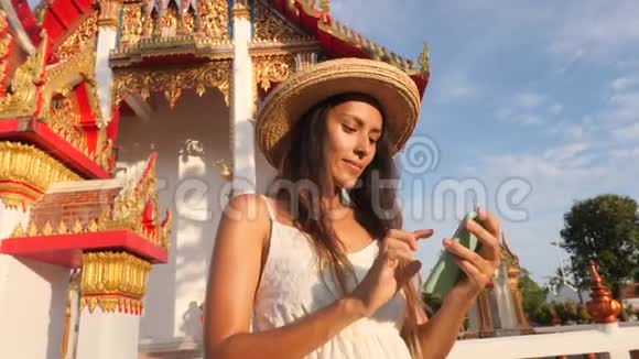 年轻的高加索旅游妇女在泰国佛寺用手机拍摄自拍照片泰国普吉岛4K视频的预览图