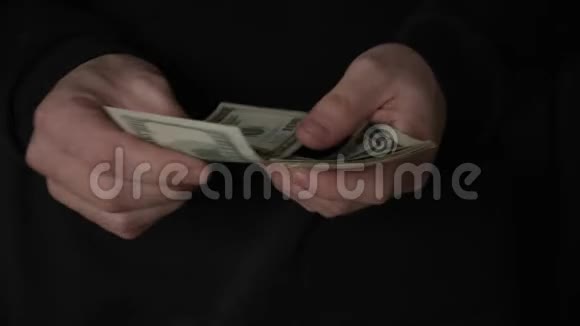 闭上男性的双手在黑暗中数出100美元的钞票视频的预览图