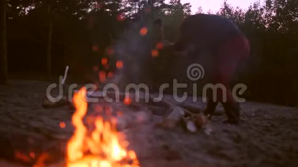 年轻人在篝火旁砍柴4K慢动作视频的预览图