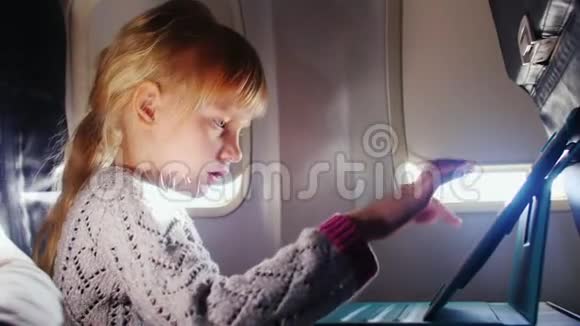 一个女孩喜欢飞机上的平板电脑视频的预览图