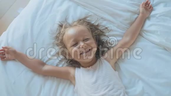 可爱的童女躺在床上看着相机笑着的肖像视频的预览图