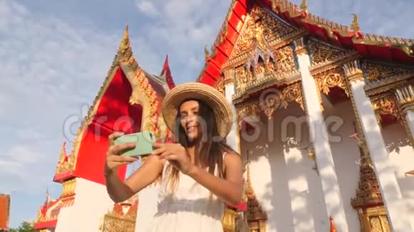 年轻的高加索旅游妇女在泰国佛寺用手机拍摄自拍照片泰国普吉岛4K视频的预览图