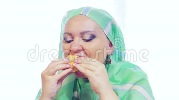 一个穿着浅绿色围巾的年轻穆斯林女人在咖啡馆里吃汉堡视频的预览图