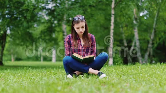 迷人的女学生在公园里看书坐在草坪上视频的预览图