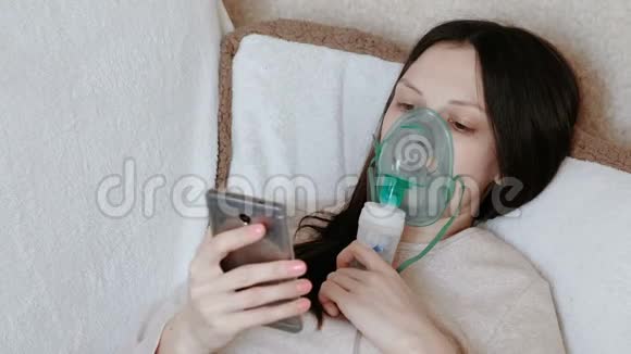 使用雾化器和吸入器进行治疗躺在沙发上聊天的年轻女子通过吸入面罩吸入视频的预览图