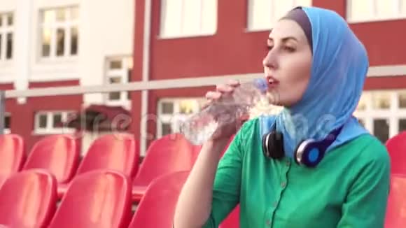 有魅力的运动型穆斯林女孩在锻炼后戴头巾饮水视频的预览图