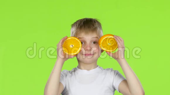 小男孩拿着一块橙色的薄片做各种鬼脸绿色屏幕视频的预览图