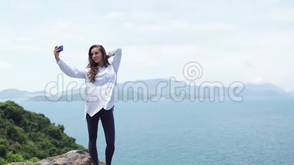 女人在山顶拍自拍照片雄伟的海岸景观视频的预览图