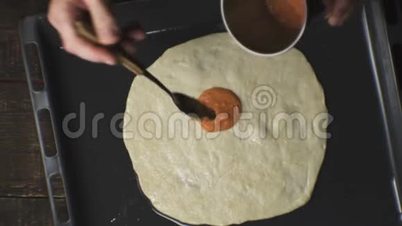 农夫把番茄酱涂在披萨面团上视频视频的预览图