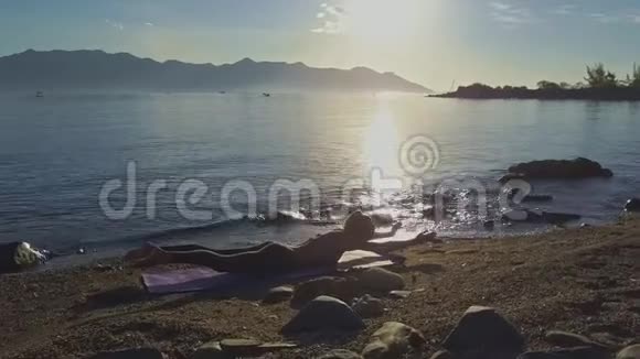 女孩用瑜伽姿势贴在胃上对抗海洋太阳反射视频的预览图
