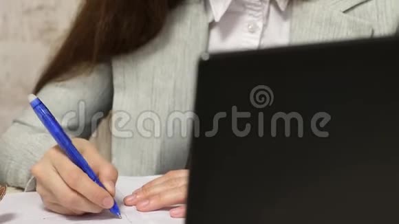 秘书在笔记本上写钢笔女孩坐在电脑办公室的椅子上在笔记本上做笔记年轻女性视频的预览图
