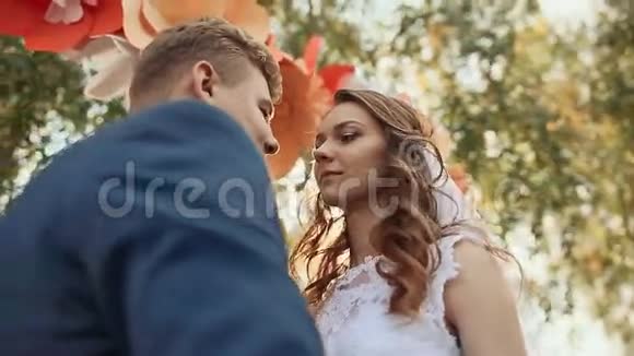 幸福的新婚夫妇在浪漫的婚礼过道上亲吻装饰以鲜花的形式它落下了一缕视频的预览图