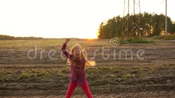 年轻的白种人女孩跳着看着路边在田野里跳舞农村场景秋天的日落慢点视频的预览图