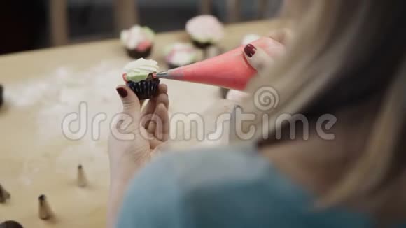 特写女性手拿着巧克力纸杯蛋糕用彩色奶油装饰它使用糕点袋视频的预览图
