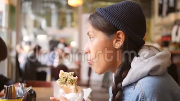 在咖啡馆里吃快餐的年轻混血少女生活方式慢动作4K视频的预览图