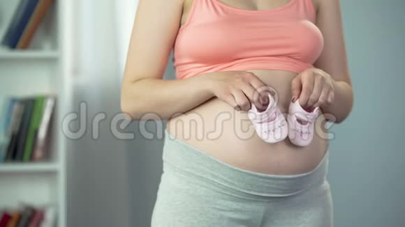 孕妇怀宝宝在大肚子上玩婴儿鞋快乐视频的预览图