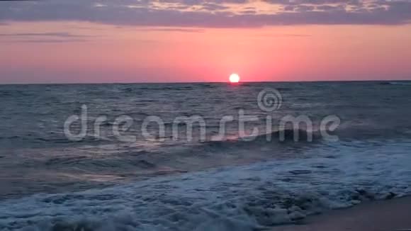 美丽的红日落在海滩上令人惊叹的色彩光束透过粉红色日落海的云景海景视频的预览图