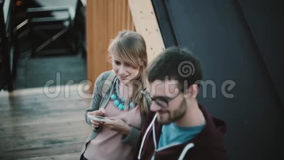 年轻漂亮的夫妇站在市中心说话幸福的女人抱着用智能手机站在男人身边视频的预览图