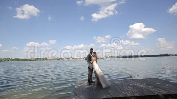 一对年轻漂亮的新婚夫妇站在湖边结婚纪念日慢动作视频的预览图
