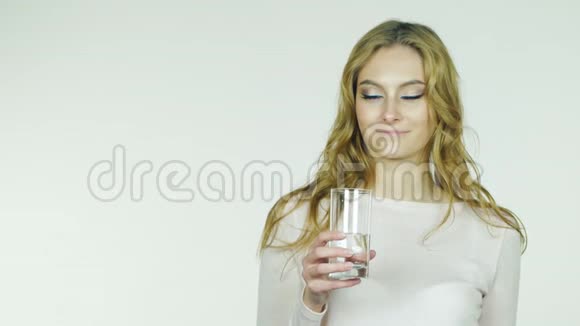 年轻女子在白色背景下从杯子里喝水视频的预览图