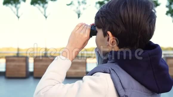 一个可爱的男孩用望远镜检查邻居视频的预览图