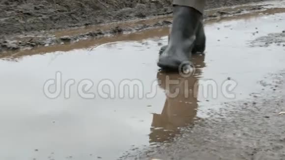 一个人穿着橡胶靴穿过泥泞的水坑视频的预览图
