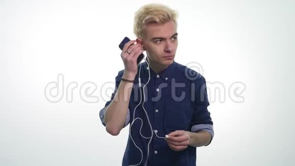 年轻的帅哥在白色背景下用耳机唱歌跳舞听音乐视频的预览图