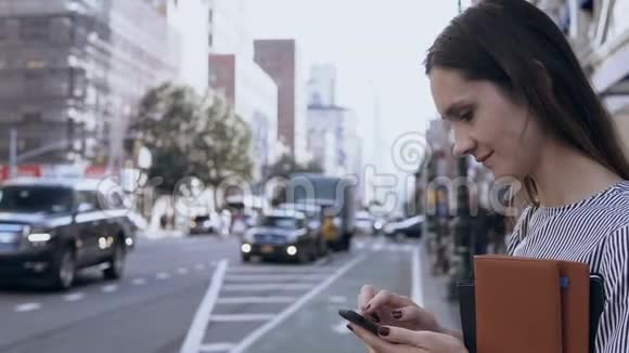 幸福美丽的女人站在纽约市中心使用智能手机打字信息视频的预览图