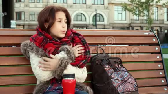 可爱的女孩坐在长凳上感觉很冷视频的预览图