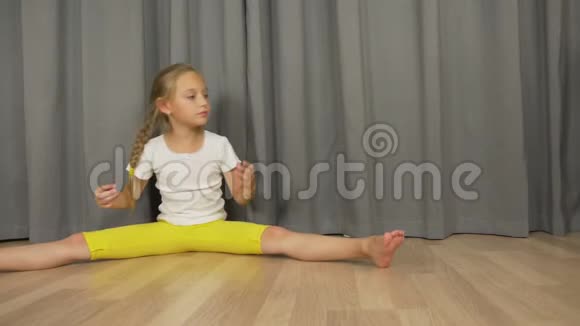 小女孩坐在客厅的地板上白人女孩伸展和跳舞女孩在室内分开视频的预览图