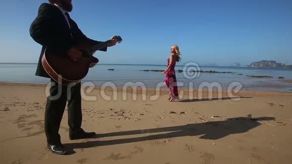 日出时在悬崖边的吉他手边跳舞的悲伤女孩视频的预览图