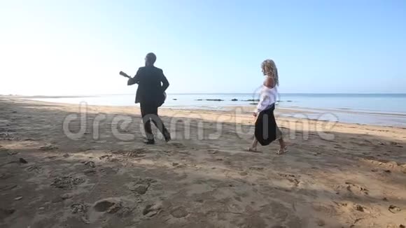 金发女孩追逐着日出时把留胡子的吉他手留在海滩上视频的预览图