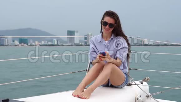 年轻女子在智能手机上留言坐在船上微笑视频的预览图