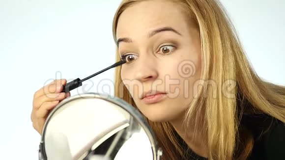 美丽的金发女人每天在镜子前化妆用小刷子画眉毛慢动作视频的预览图