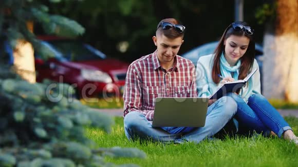 在公园里用笔记本电脑工作的男女学生视频的预览图