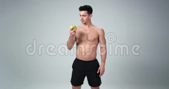 一位男性健身模特对苹果说是快乐健康的生活白色背景4k视频的预览图
