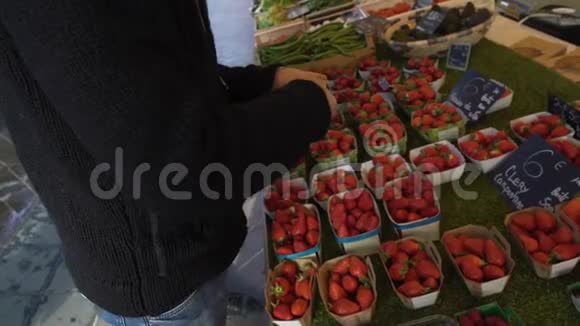 男人数着钱在当地市场上给女售货员买新鲜草莓视频的预览图