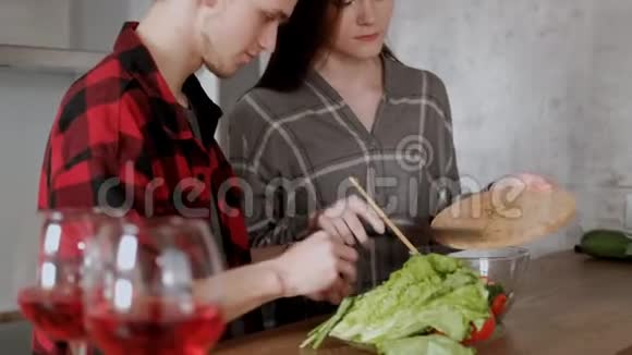 年轻漂亮的一对穿格子衬衫的夫妇正在家厨房做饭一个女人和一个男人切菜做菜视频的预览图