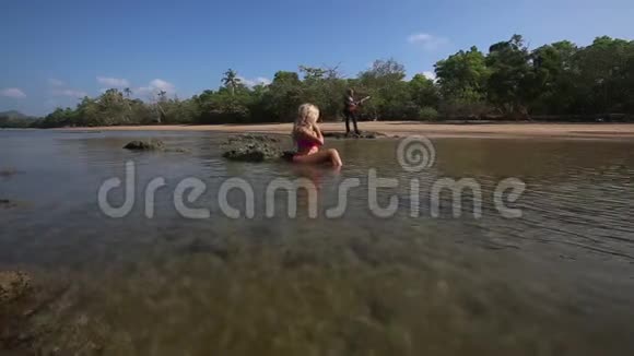 穿着泳装的女孩躺在海里抚平头发吉他手的演奏视频的预览图