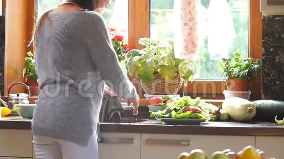 漂亮的年轻妈妈在做厨房工作在水槽里洗抹布视频的预览图