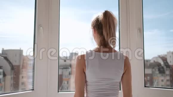 年轻漂亮的运动女性金发穿着白色运动服在家里的阳台上做瑜伽和伸展运动准备就绪视频的预览图