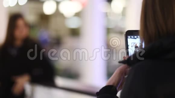 在交易中心的露台上两张漂亮的棕色头发的花柱在智能手机上拍照视频的预览图